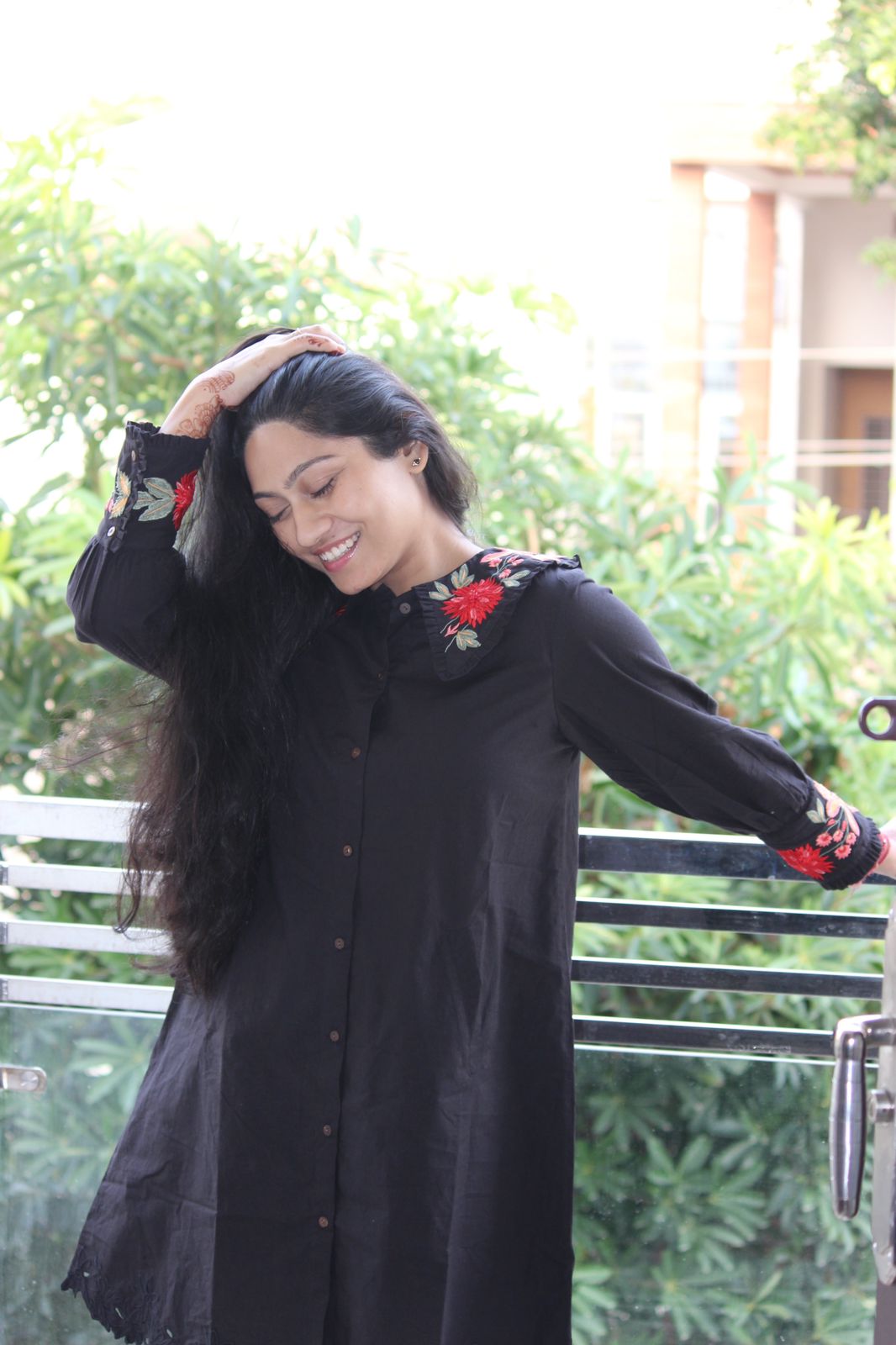 Woman wearing a black dress with floral embroidery outdoors