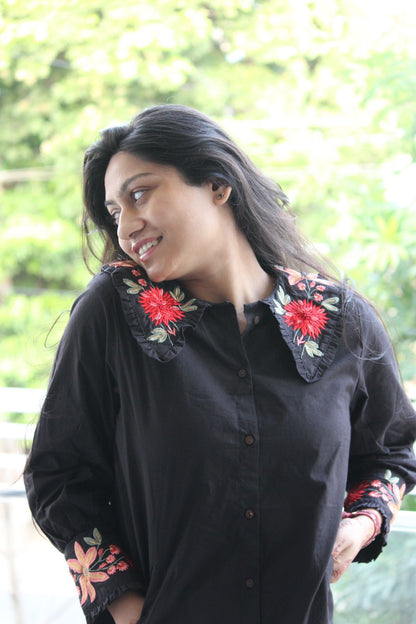 Woman wearing a black shirt with floral embroidery outdoors